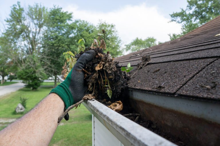 cleaning gutters filled with leaves & sticks