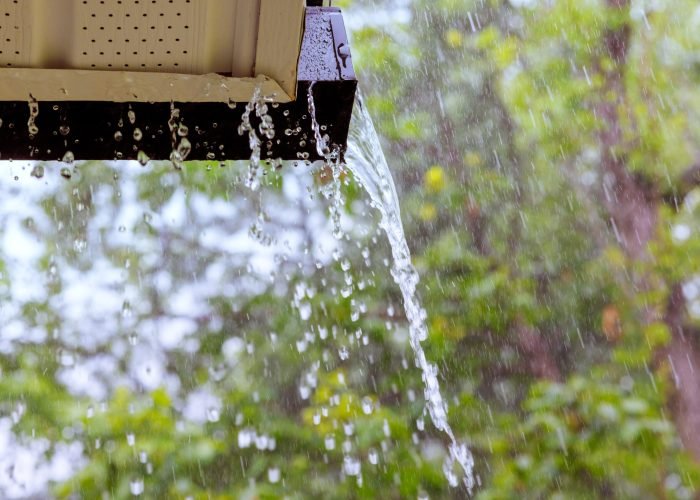 during heavy rain, water cascades from the overflowing gutters.